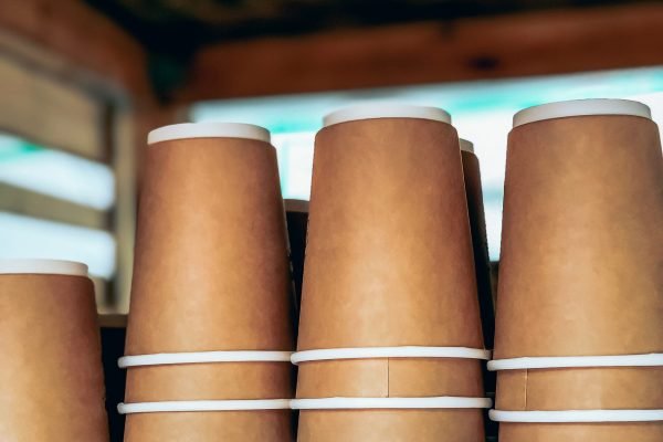 Placeit. Disposable coffee cups piles in outdoor street market cafe. Street food and drinks take away waste problem concept. Ecology pollution.